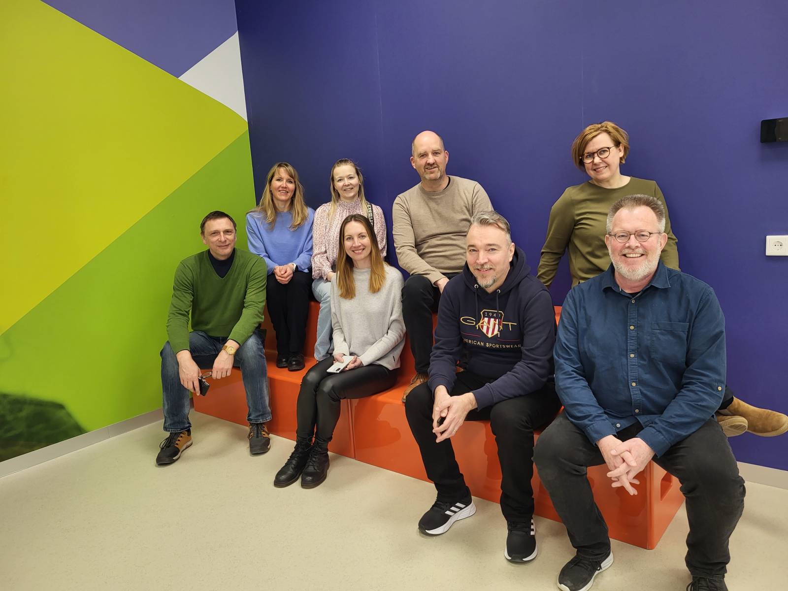 Eight people sitting on a bench in a classroom.