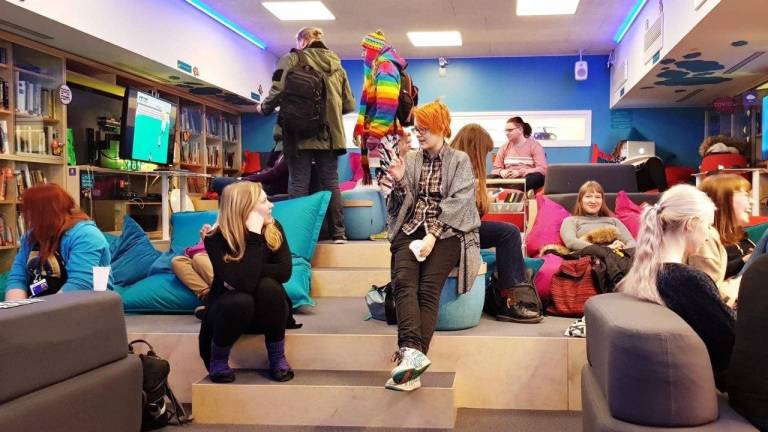 Ihmisiä istumassa Oasiksessa penkeillä ja sohvilla.