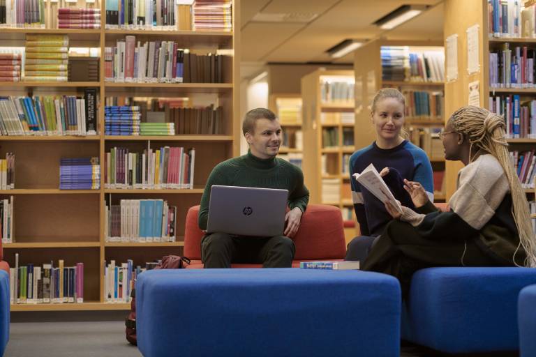 Kolme henkilöä keskustelee kirjastossa.