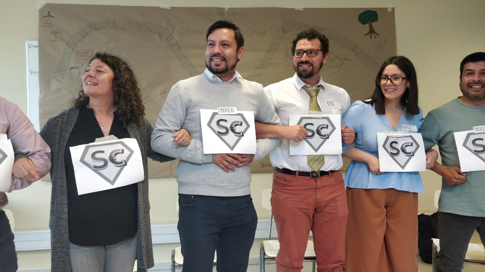 Five people standing in a row and holding a sign "SC" in their hands.