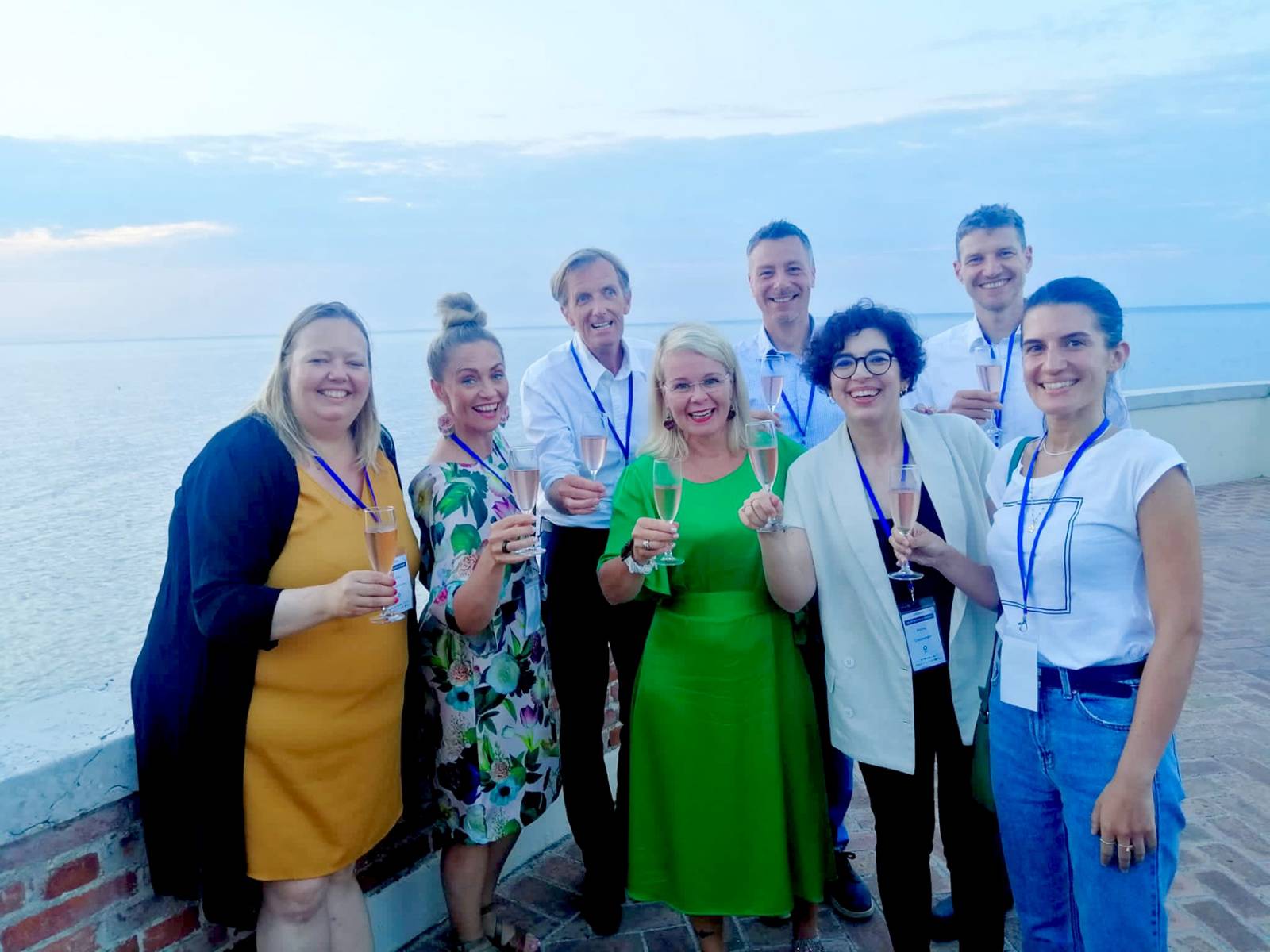 Tutkimusprojektiryhmä kuohuviinilasien kanssa italialaisessa järvimaisemassa.