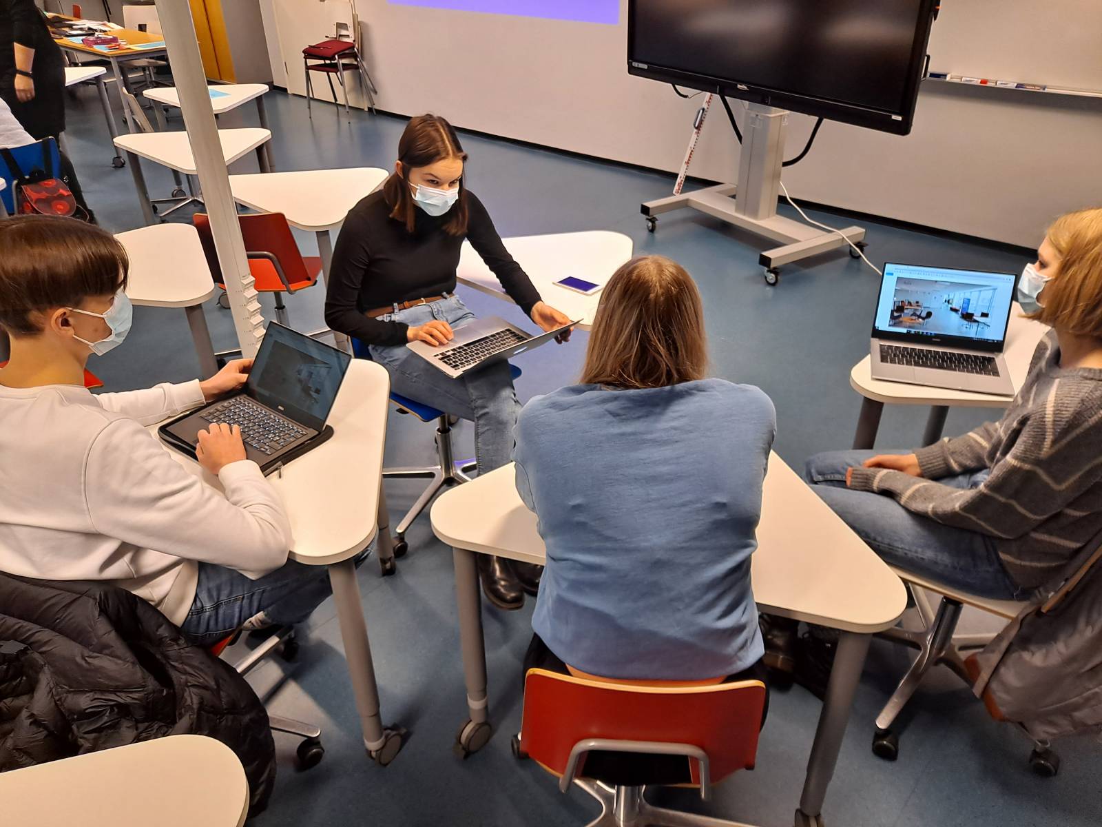 Opiskelijat suunnittelevat luokassa oppimisympäristöä pienryhmässä tietokoneiden kanssa.