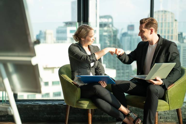 Kaksi hyväntuulista myyjää istuvat nojatuoleilla ja solmivat kaupan.