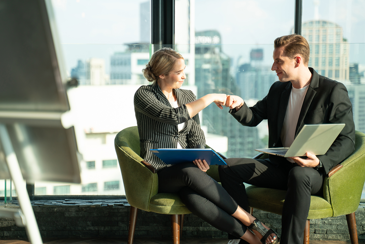 Kaksi hyväntuulista myyjää istuvat nojatuoleilla ja solmivat kaupan.