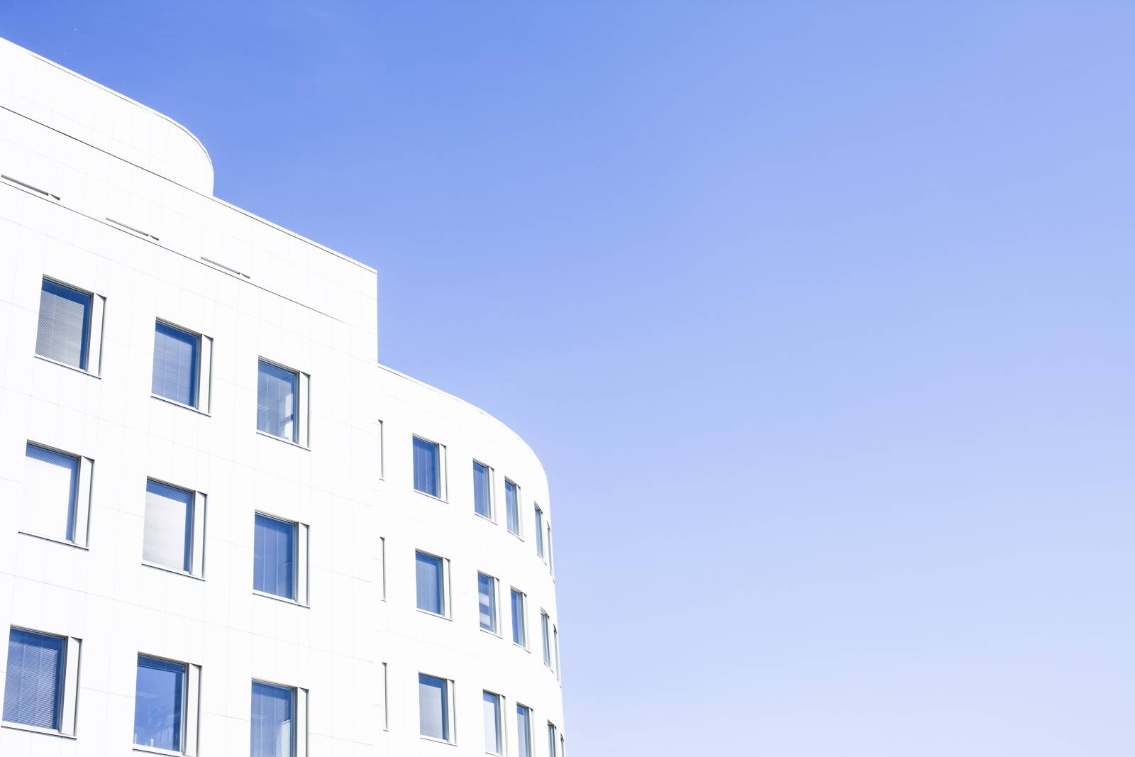 Valkoinen rakennus, jossa paljon ikkunoita ja sininen taivas.