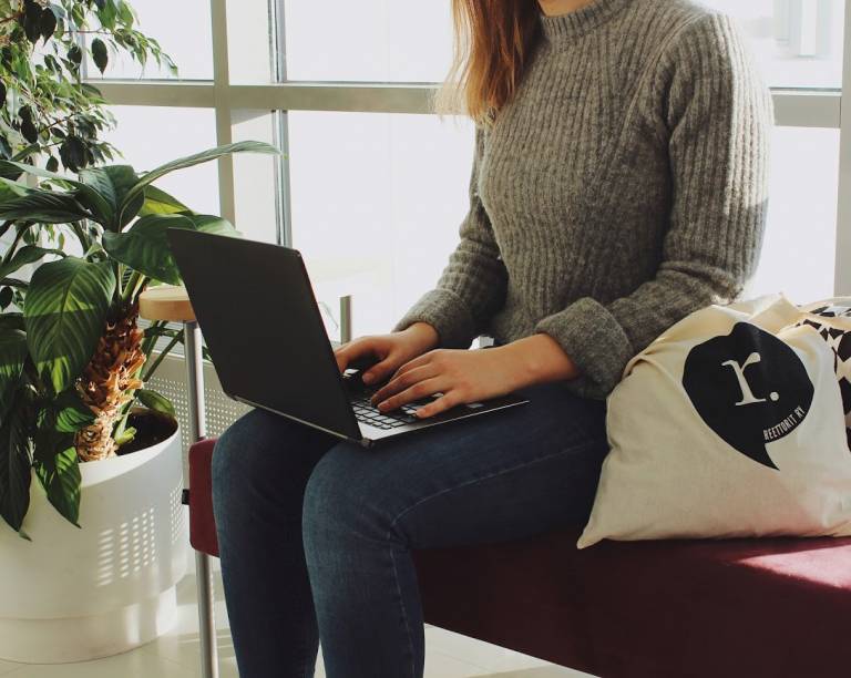 Opiskelija istuu tietokone sylissään