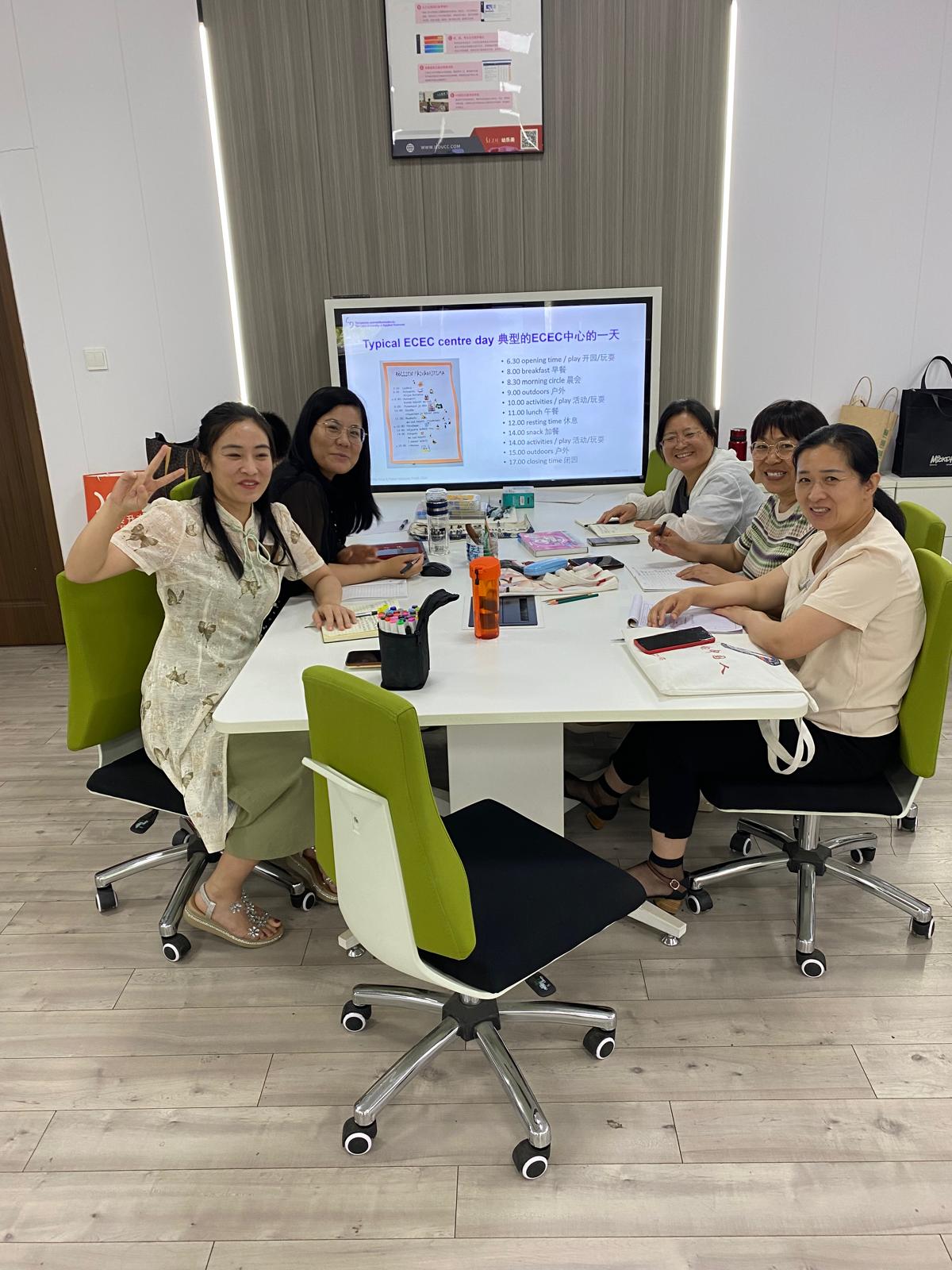 Five Chinese people sitting around the table, smiling.