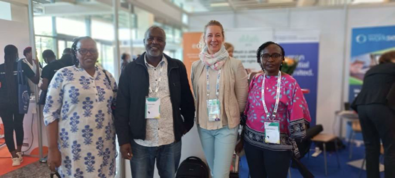 Four people standing next to each other smiling.