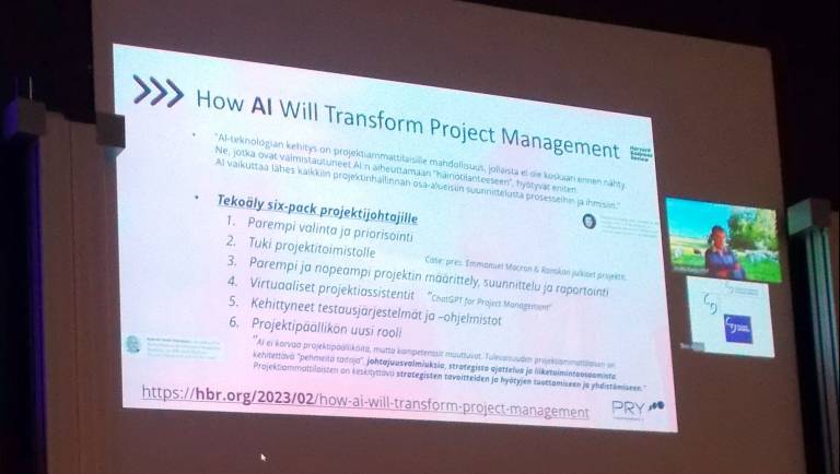 Luentosalinäkymä, jossa projektihallintapäivän tervetulotiedot heijastettuna seinalle