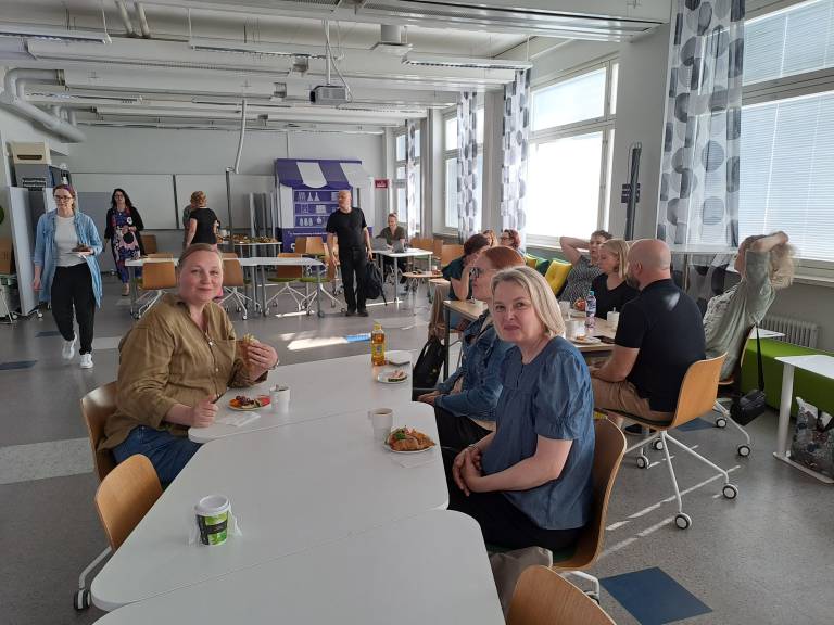 Ihmisiä istumassa pitkien pöytien äärellä.