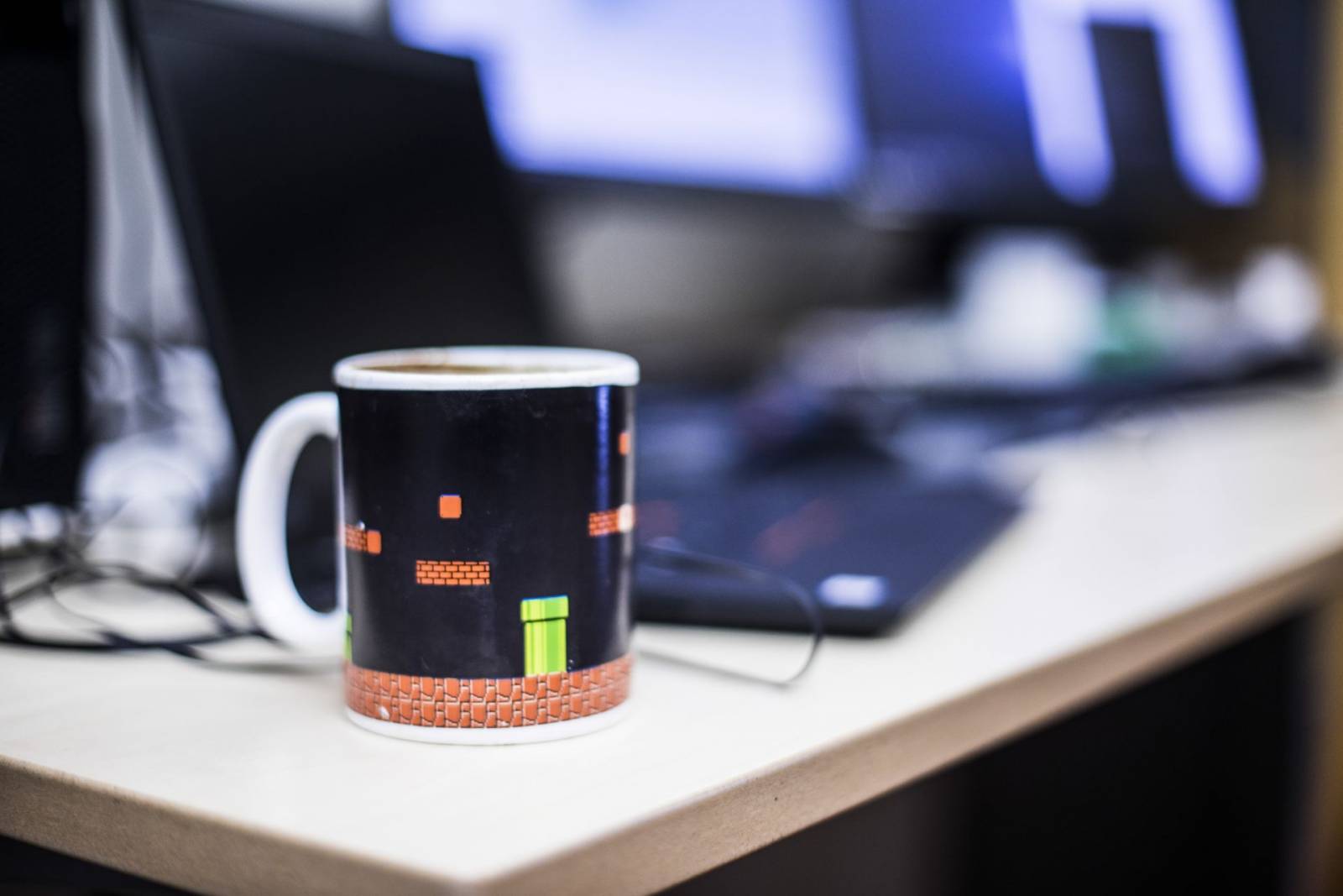 Kahvikuppi ja kannettava tietokone pöydällä.