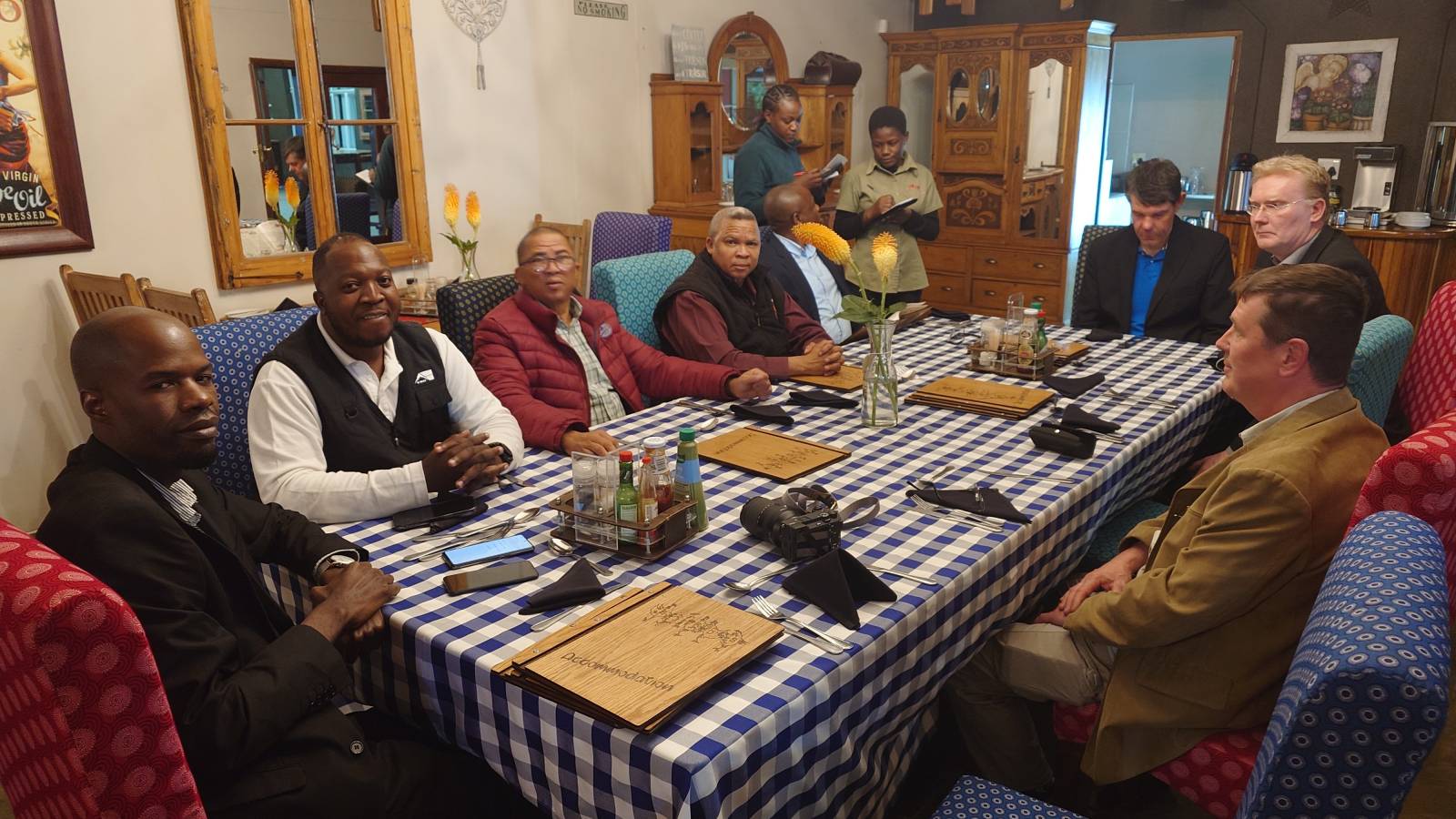 Ryhmä ihmisiä istumassa pöydän ympärillä hymyillen