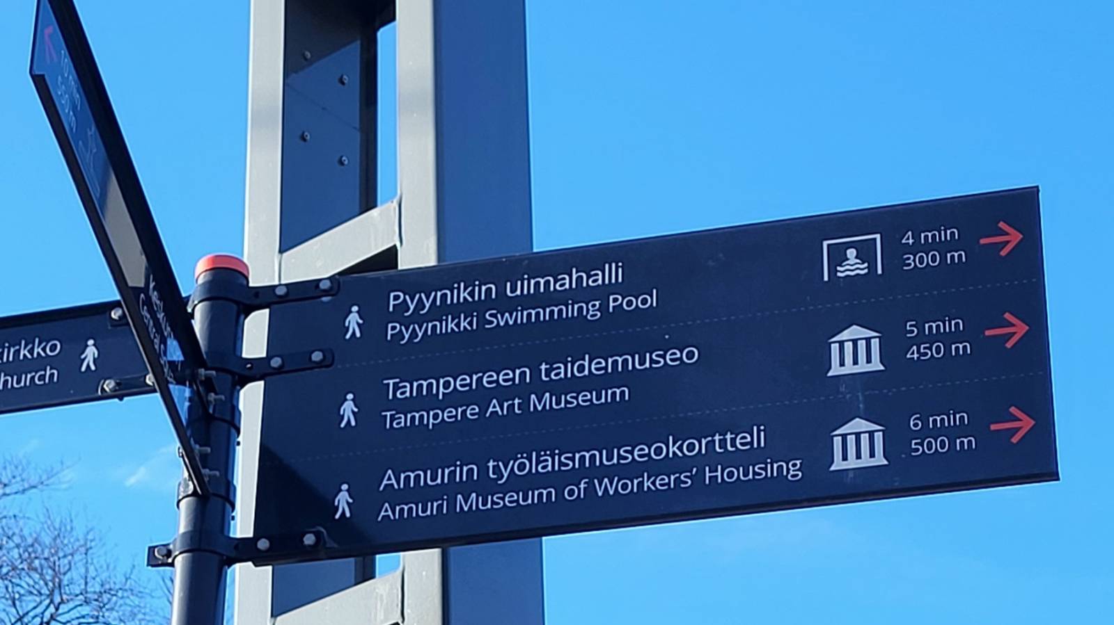 Opastekyltti, jossa matkojen pituuksia ja matka-aikoja Pyynikin uimahallille, Tampereen taidemuseoon ja Amurin työläismuseokortteliin.