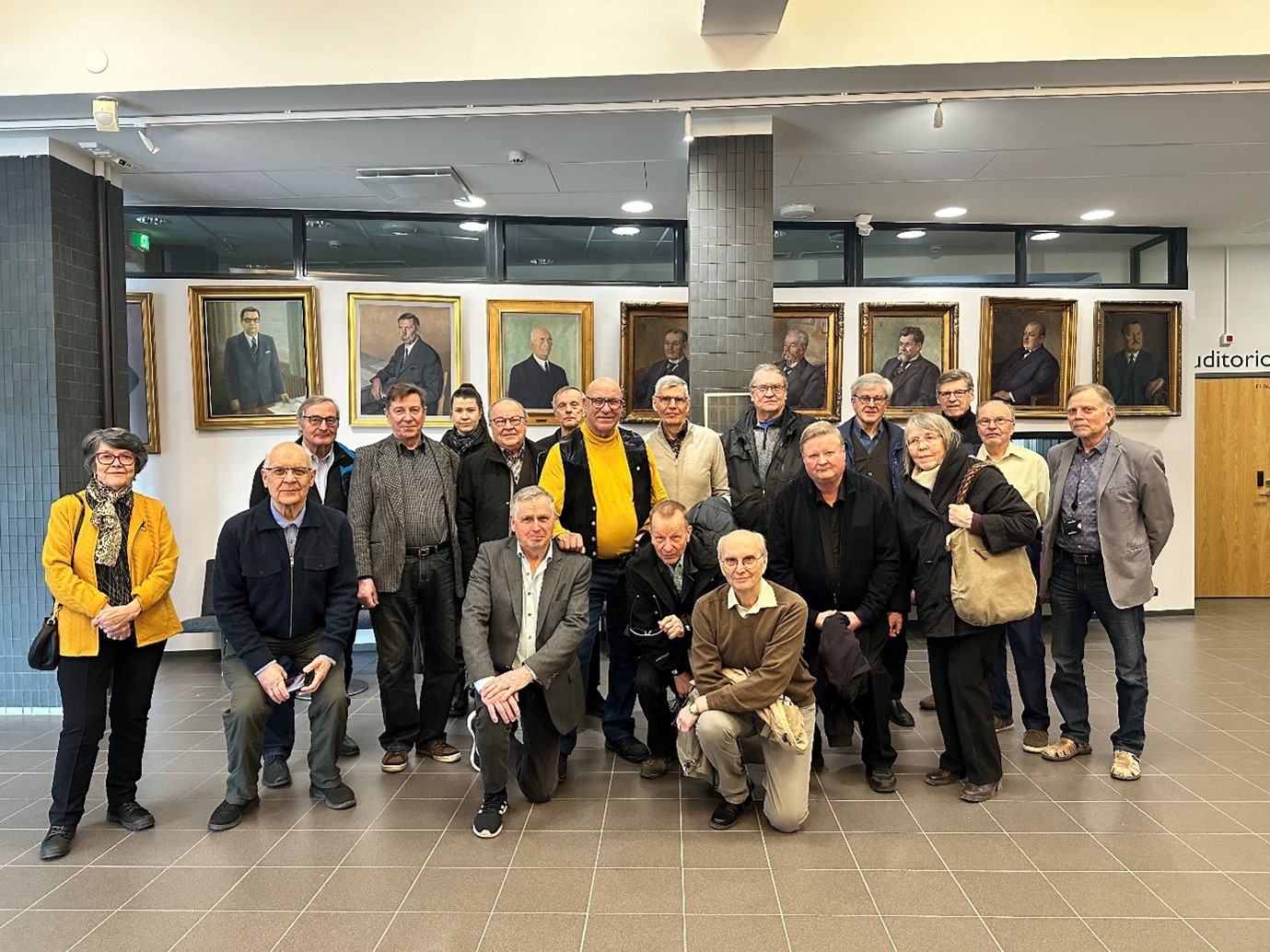 Ihmisiä seisomassa ryhmämuodostelmassa aulassa.