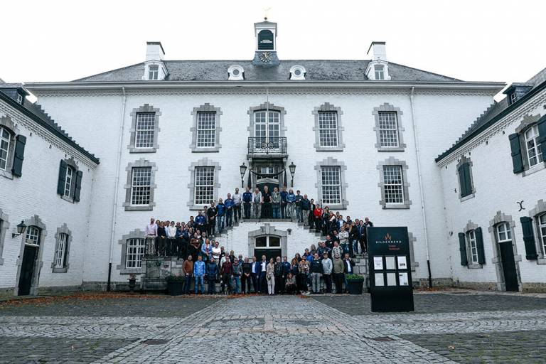 Iso valkoinen talo, jonka edessä seisoo paljon ihmisiä.