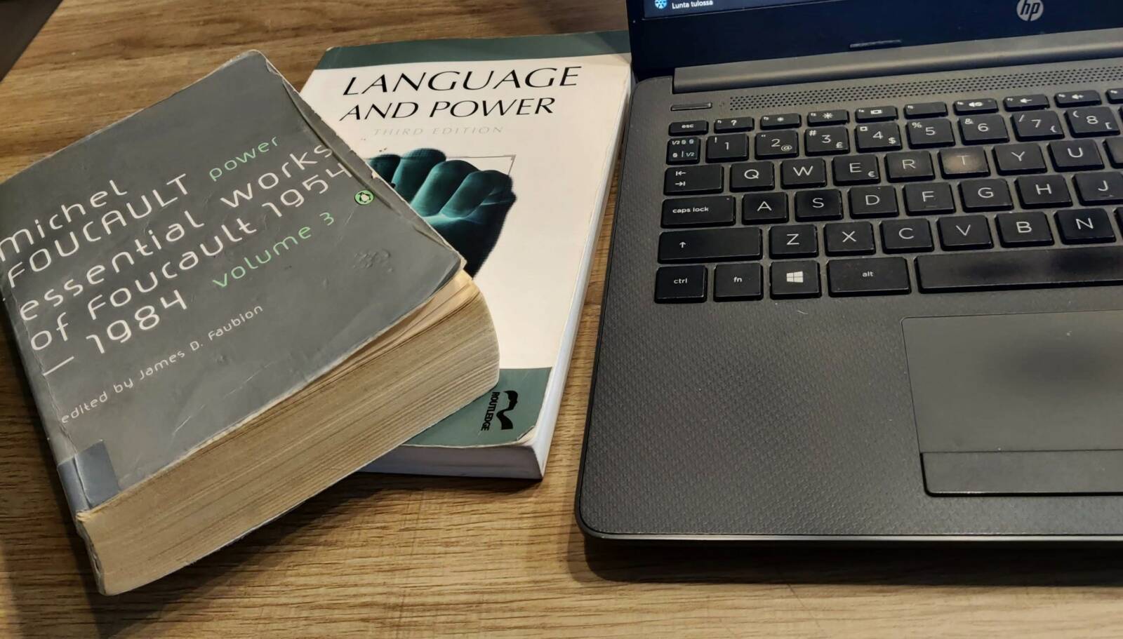 Pöydällä kannettava tietokone sekä oppikirjoja.