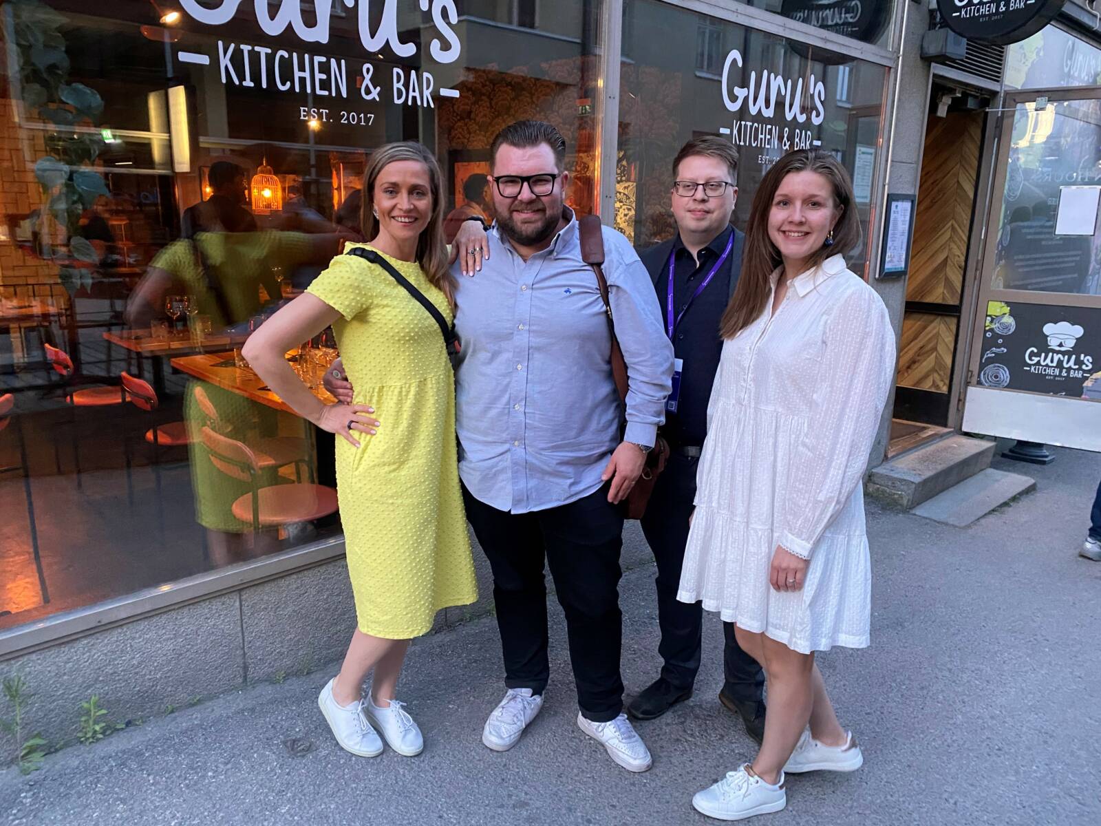 Neljä henkilöä seisomassa ulkona ravintolan edessä.