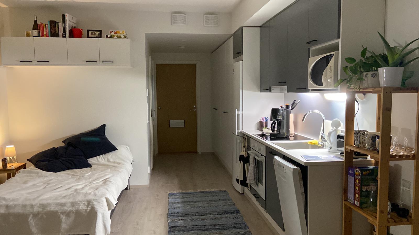 Opiskelija-asunto jossa sänky ja keittiö.