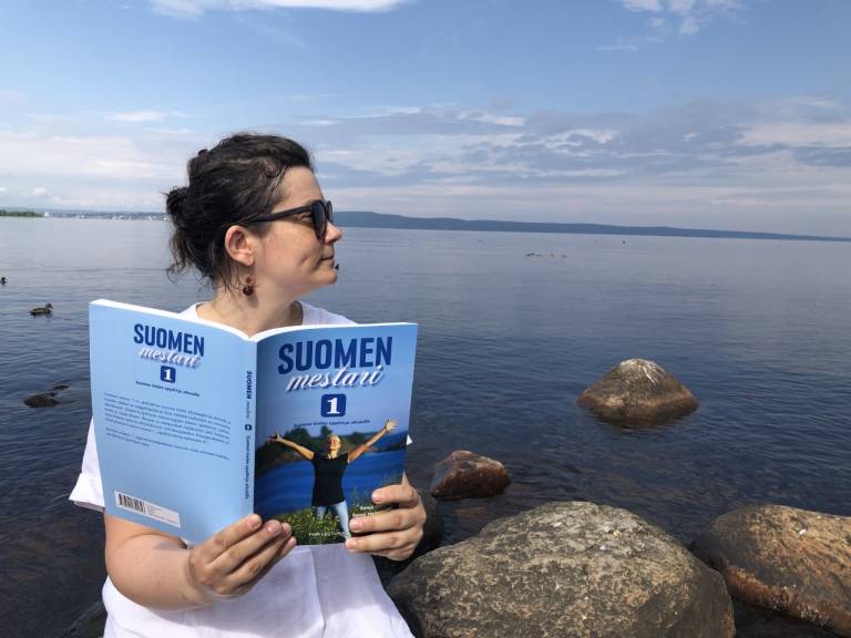 Valeriia reading a book by the lake.