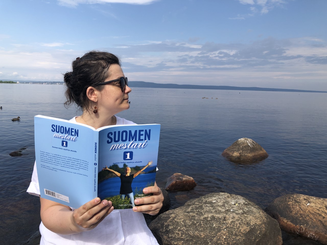 Valeriia reading a book by the lake.