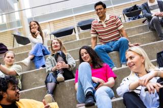 A group of students smiling and sitting on the stairs
