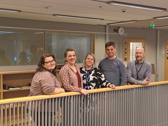 Five people are leaning on the railing.