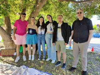 Vierailijamme opiskelijoiden kanssa. Kuusi iloista ihmistä puiden varjoissa.