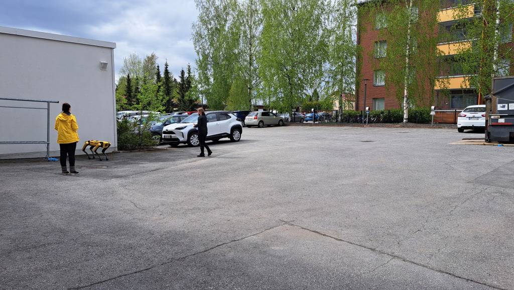 Spot-robotti ja kaksi ihmistä ulkona.